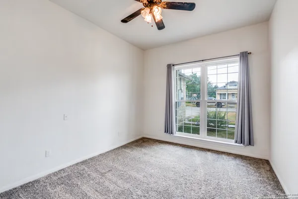 an empty room with a window and a ceiling fan