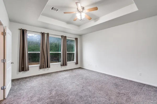 a view of an empty room with a window and kitchen view