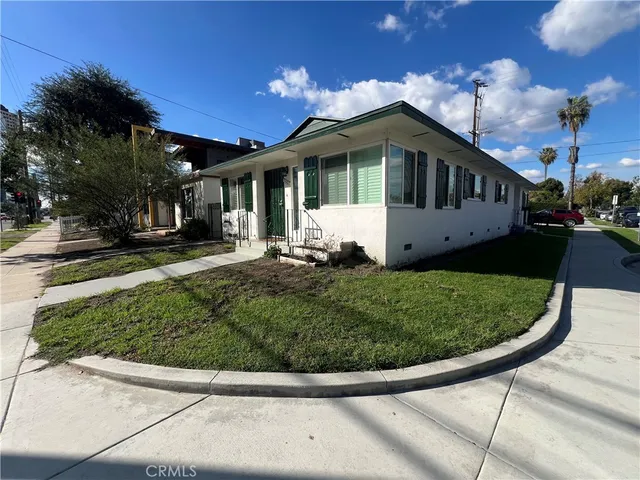 a view of a white house with a small yard and potted plants