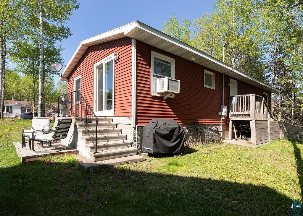 216 13th Street Proctor, MN 55810 - Photo 2 of 18 Red siding exterior with white trim, featuring a sliding glass door leading to a concrete staircase with wrought iron railings