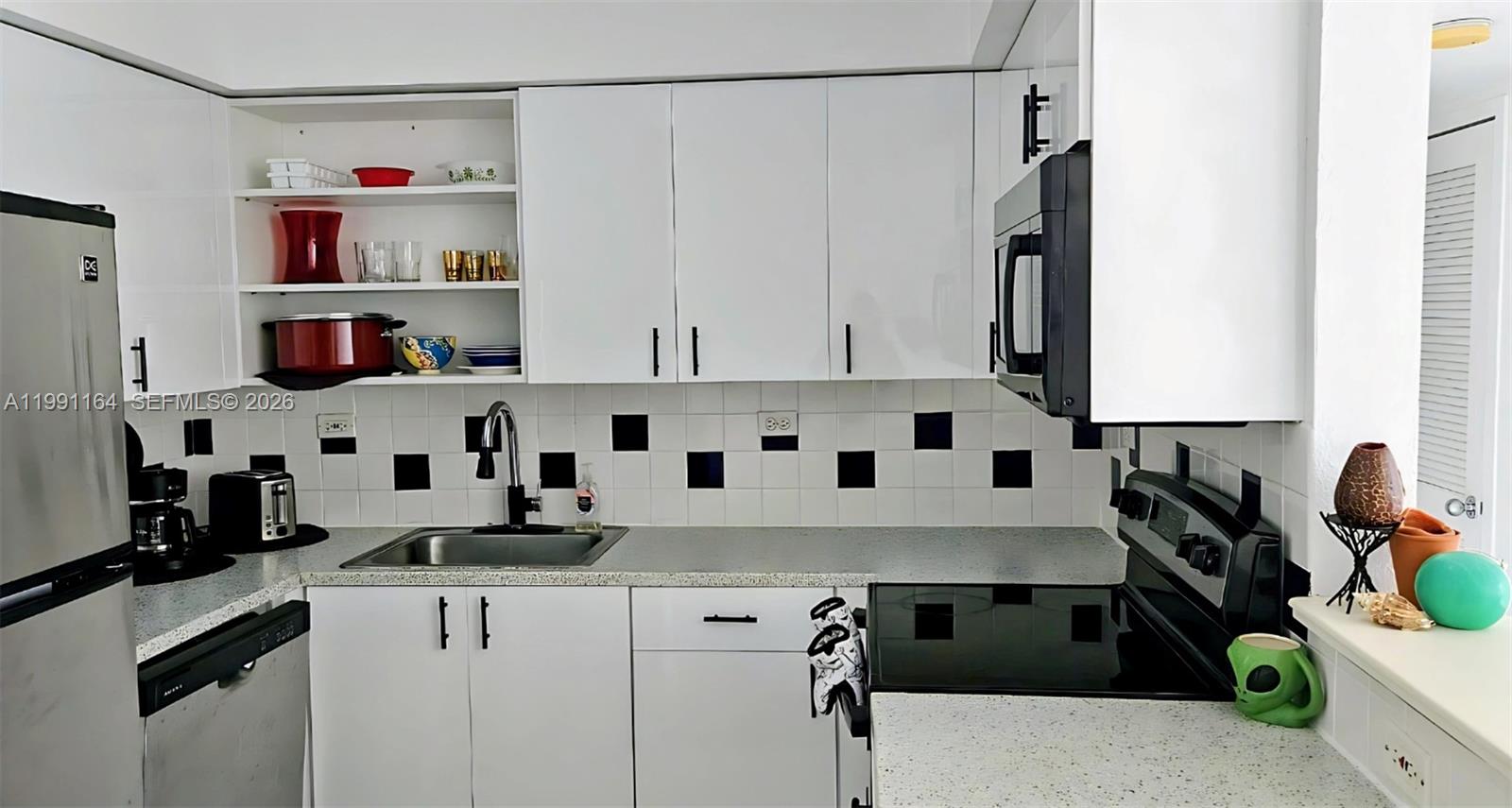 1500 Bay Road, Unit 854S Miami Beach, FL 33139 - Photo 13 of 20 a kitchen with stainless steel appliances a white cabinets and a counter top space