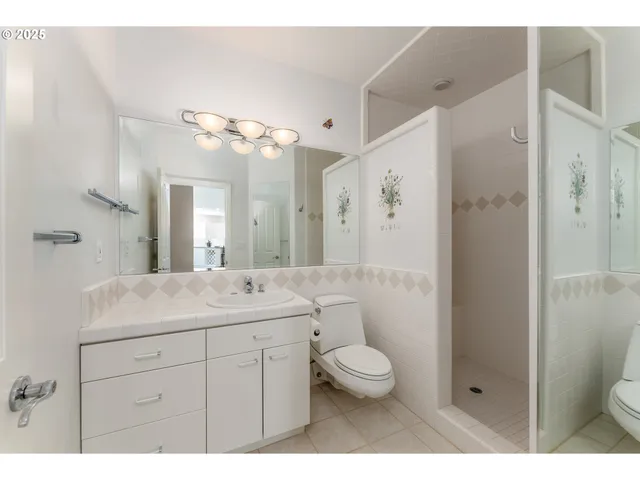 a bathroom with a sink a toilet a mirror and shower