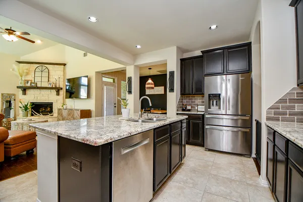 a kitchen with stainless steel appliances granite countertop a refrigerator a sink and a stove