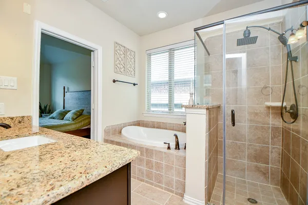 a en suite bathroom with a granite countertop sink and a large mirror