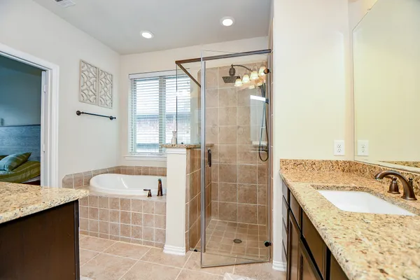 a bathroom with a granite countertop sink a mirror and shower