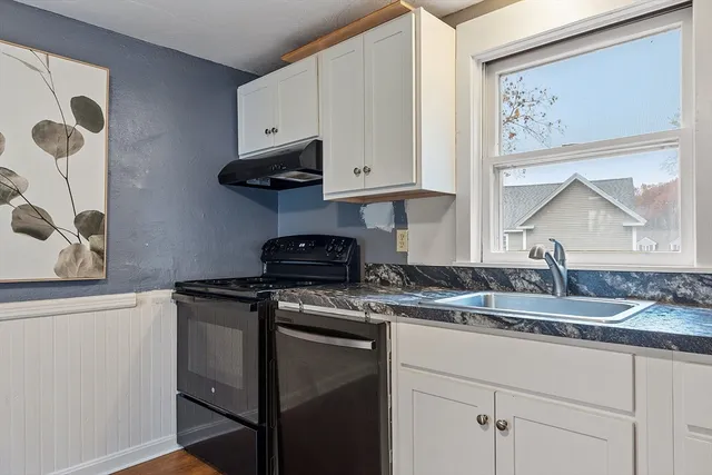 a kitchen with granite countertop a sink a stove and cabinets