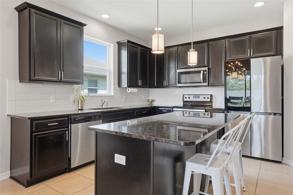 3933 Wind Dancer Circle St. Cloud, FL 34772 - Photo 10 of 35 a kitchen with stainless steel appliances granite countertop a sink a stove and a refrigerator