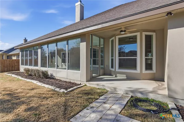 an empty room with wooden floor chandelier and windows