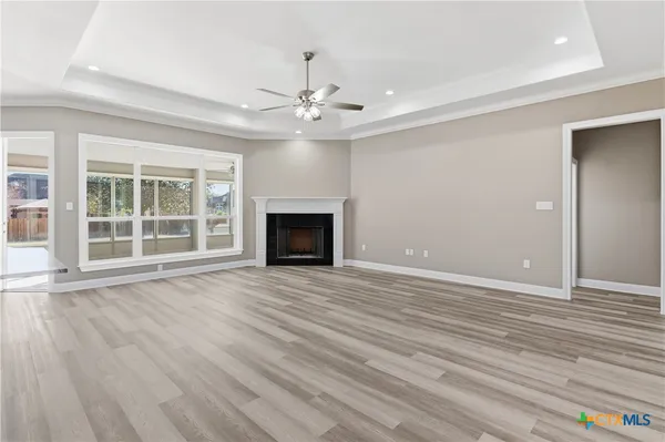 a view of an empty room with wooden floor and a fireplace