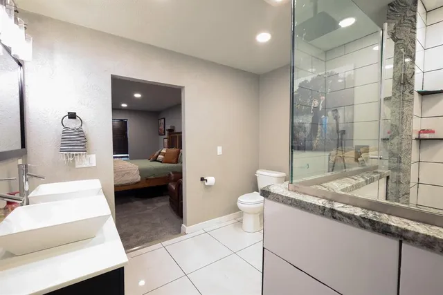 a en suite bathroom with a granite countertop sink a toilet and shower