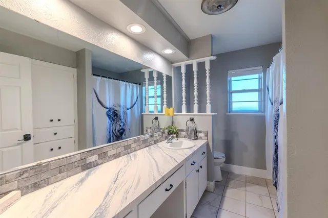 a bathroom with a granite countertop sink a mirror and a bathtub