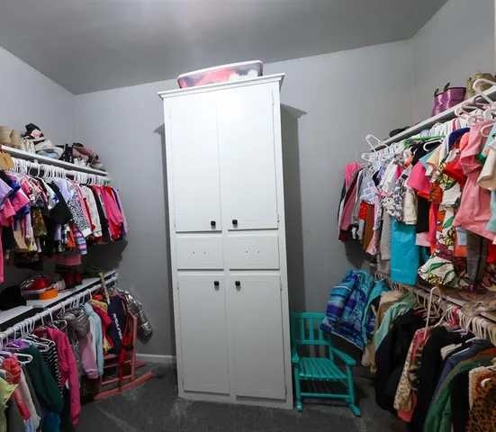 a view of walk in closet with clothes and shoes