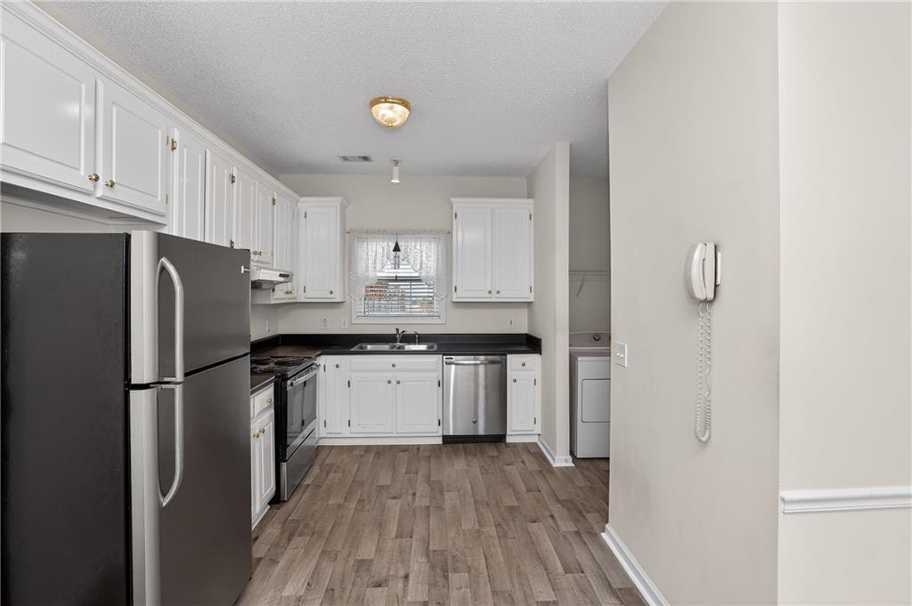 181 Windsor Circle Stockbridge, GA 30281 - Photo 21 of 49 a kitchen with stainless steel appliances granite countertop a refrigerator a sink dishwasher and a stove with wooden floor