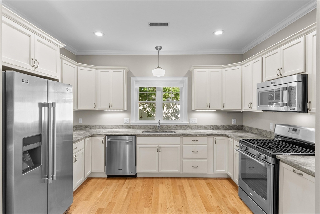 4 Emerald Way, Unit 4 Salisbury, MA 01952 - Photo 16 of 40 a kitchen with stainless steel appliances granite countertop a stove a sink dishwasher a refrigerator and white cabinets with wooden floor