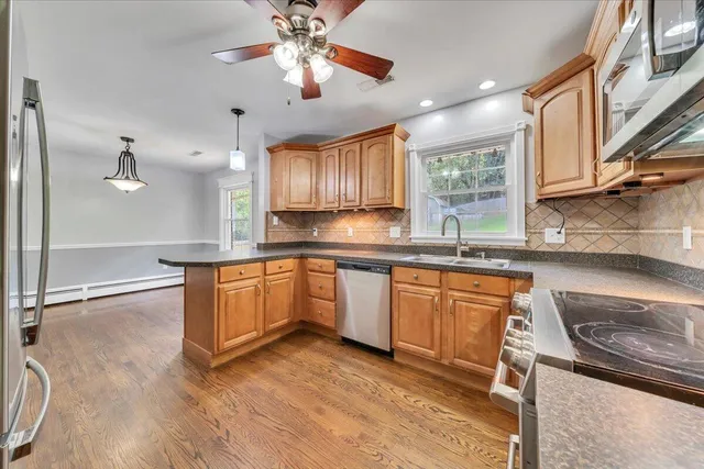 a kitchen with stainless steel appliances granite countertop a sink a stove cabinets and wooden floor