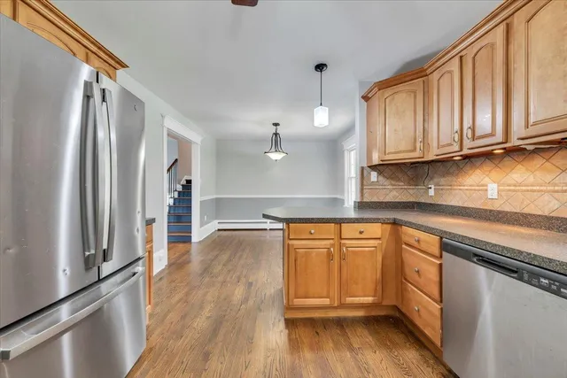 a kitchen with stainless steel appliances granite countertop a refrigerator a sink dishwasher and wooden cabinets with wooden floor