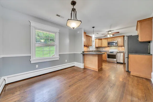 a kitchen with stainless steel appliances granite countertop a stove top oven a sink dishwasher and a refrigerator with wooden floor