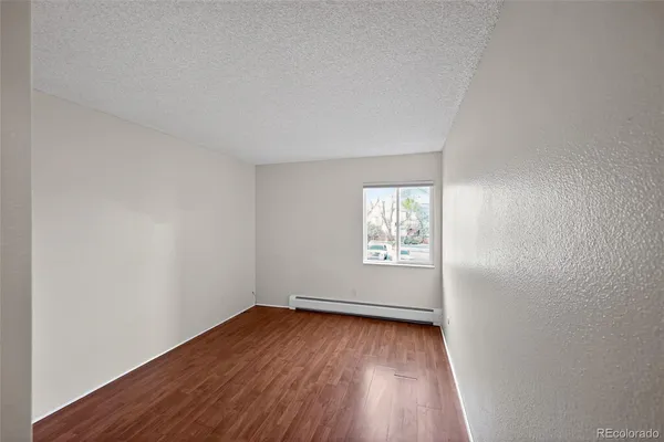 a view of an empty room with wooden floor and window