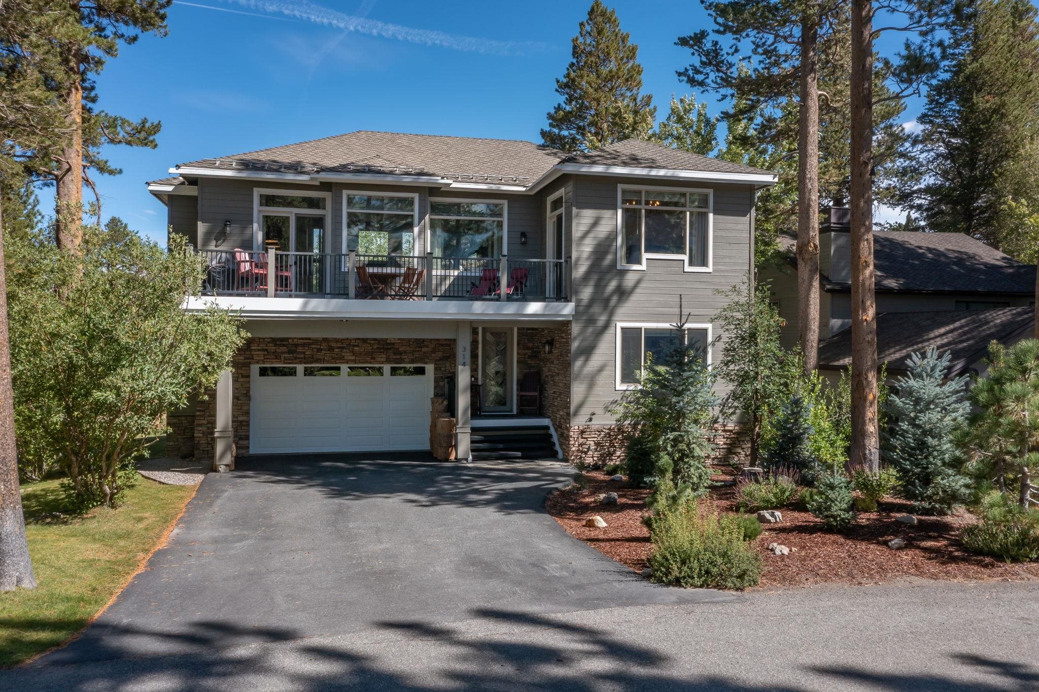 314 Ridge Way Mammoth Lakes, CA 93546 - Photo 1 of 6 Contemporary two-story exterior with gray siding and stone accents, featuring a multi-pane garage door, an upper-level balcony, and a paved driveway