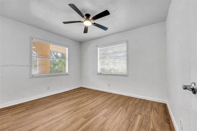 an empty room with wooden floor chandelier fan and closet area