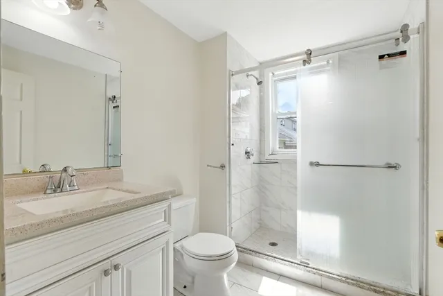 a bathroom with a shower sink vanity mirror and toilet
