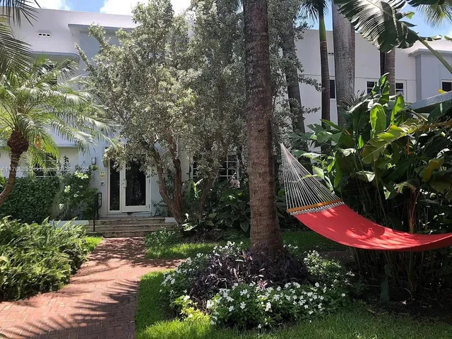 a view of a backyard with potted plants and large trees