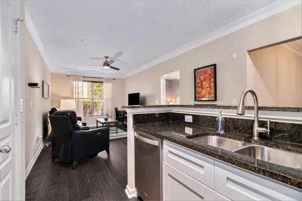 a kitchen with granite countertop a sink dishwasher a stove and a dining table with wooden floor