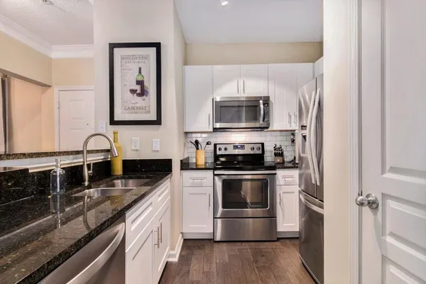 a kitchen with stainless steel appliances granite countertop a stove a sink and a microwave