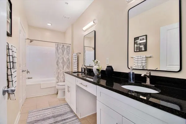 a bathroom with a granite countertop sink a toilet a mirror and shower