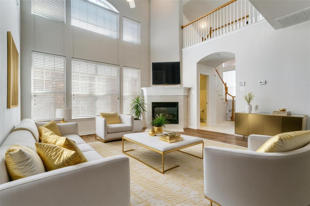 Living area with a tile fireplace, wood finished floors, a high ceiling, and arched walkways