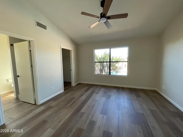an empty room with wooden floor fan and windows