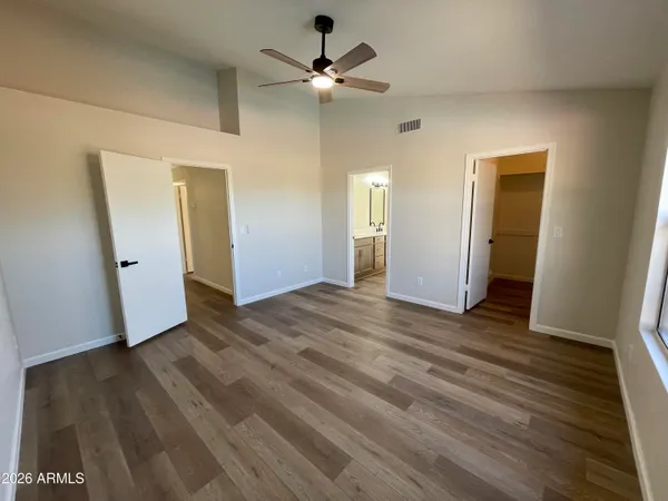 an empty room with wooden floor and a ceiling fan
