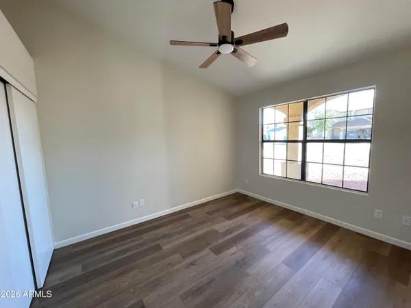 an empty room with wooden floor fan and windows