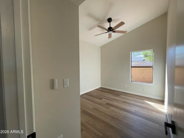 a view of empty room with wooden floor and fan