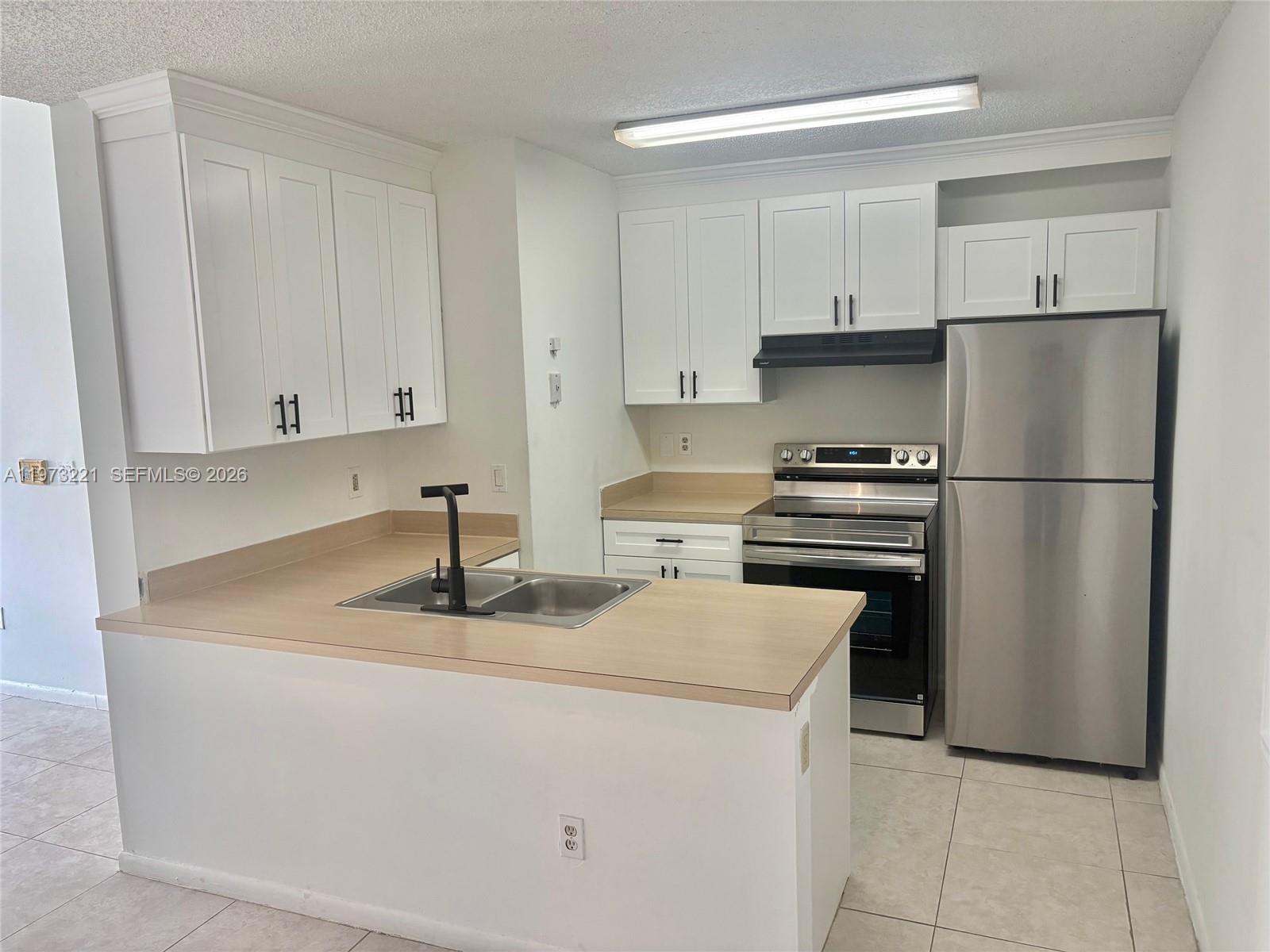18324 Northwest 68th Avenue, Unit H Hialeah, FL 33015 - Photo 4 of 9 a kitchen with appliances a sink and cabinets