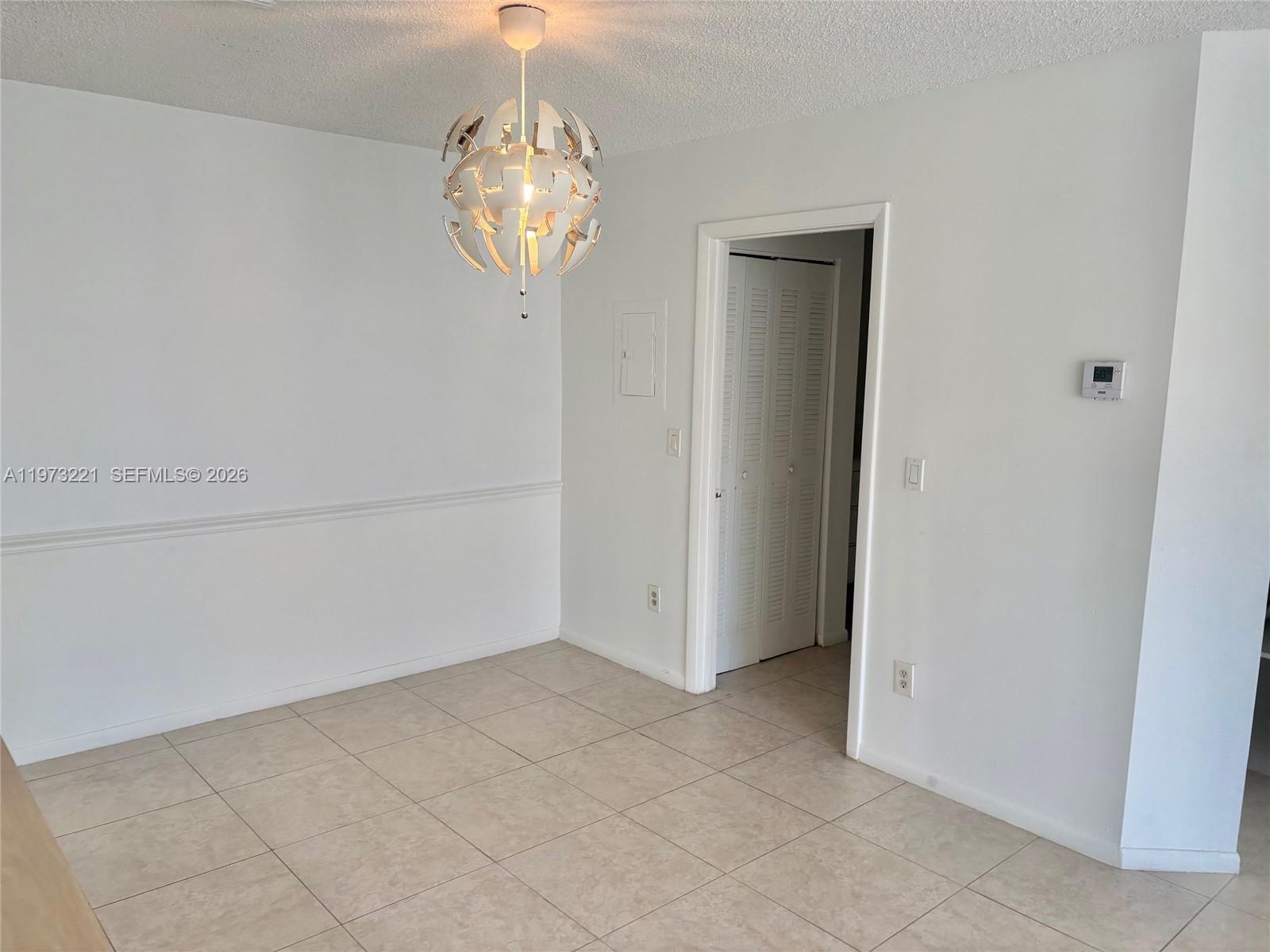 18324 Northwest 68th Avenue, Unit H Hialeah, FL 33015 - Photo 9 of 9 a view of an empty room with a chandelier