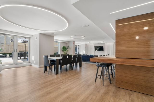 a dining hall with stainless steel appliances granite countertop a table and chairs with wooden floor