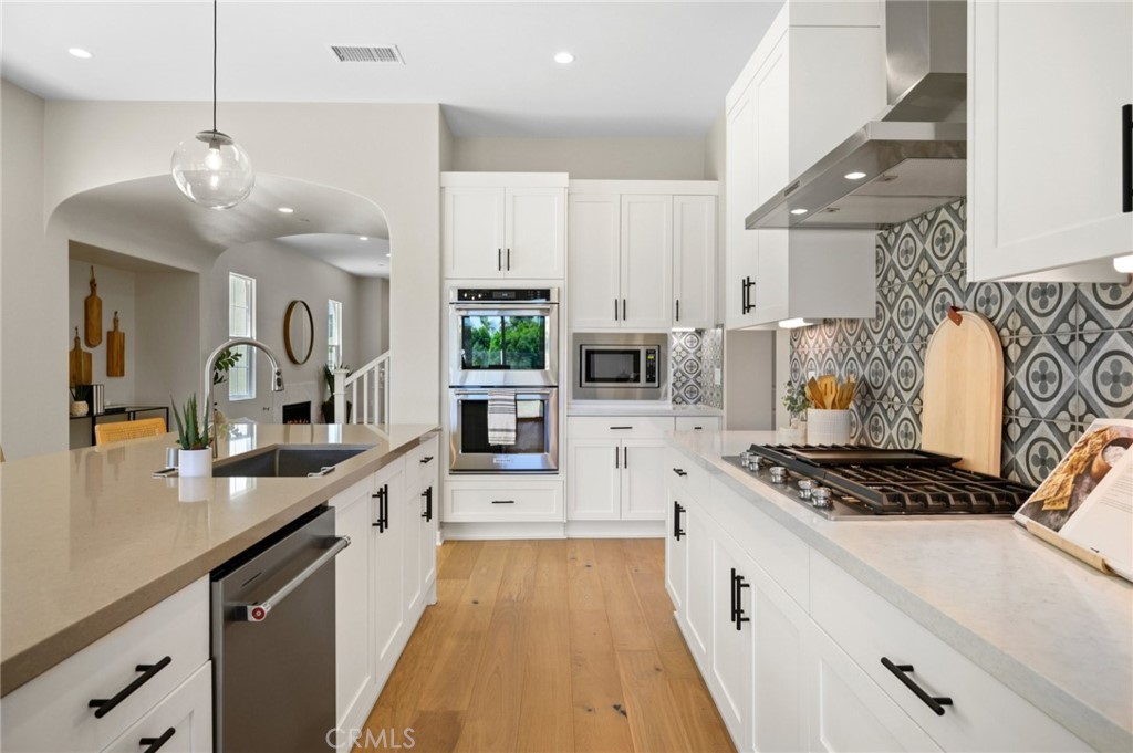 a large kitchen with stainless steel appliances a stove sink and cabinets