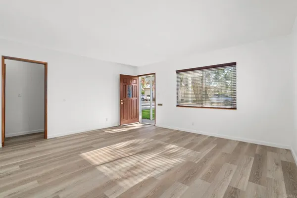 a view of an empty room with window and wooden floor