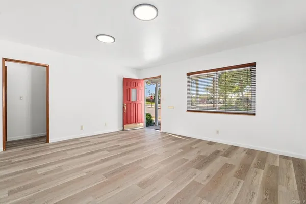 a view of an empty room with wooden floor and window