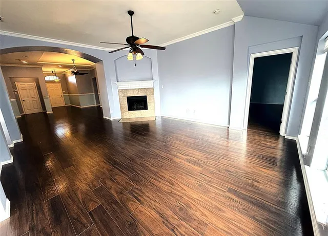 a view of an empty room with wooden floor fireplace and a window