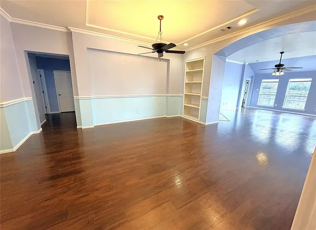 a view of a livingroom with wooden floor a ceiling fan and windows