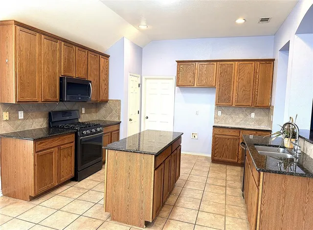a kitchen with granite countertop a stove top oven microwave and cabinets