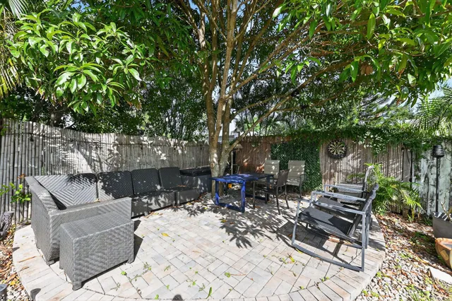 a view of a patio with table and chairs potted plants and large tree