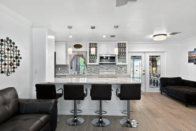 a kitchen with granite countertop a kitchen island white cabinetry and chairs