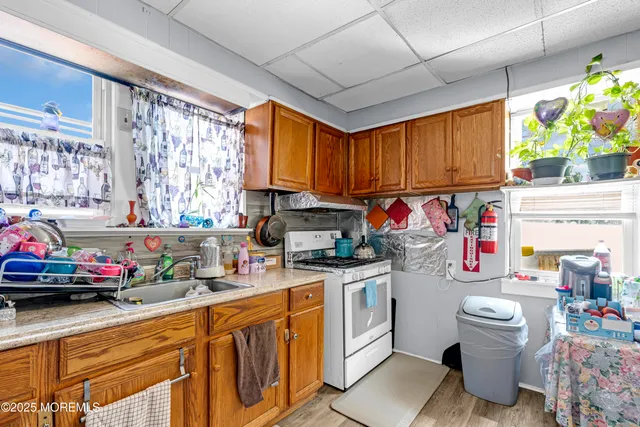a utility room with stainless steel appliances granite countertop a sink a stove and a window