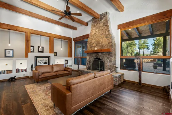 a living room with furniture large window and wooden floor
