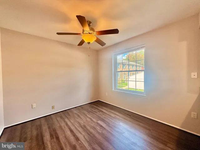 an empty room with wooden floor fan and windows
