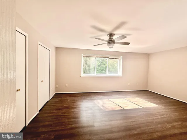 an empty room with wooden floor chandelier fan and windows
