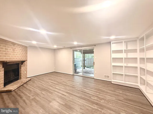 an empty room with wooden floor fireplace and windows
